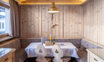A cozy dining area with wooden paneling and a round table decoration. The decor radiates an inviting alpine atmosphere.