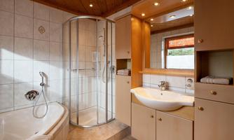 A modern bathroom with a shower and a bathtub. Bright wood and tile surfaces create a welcoming atmosphere.