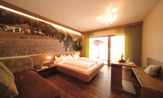 A modern hotel room with a large bed and a cozy seating area. The room has a balcony and beautiful wall decor.