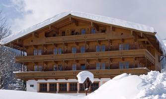 A beautifully designed chalet in the snow. The sky is blue and the surroundings are wintry.