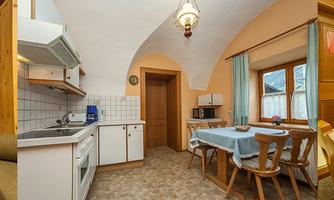 A bright and cozy holiday room with wooden interior and window light. The kitchen is modern and well-equipped, ideal for a pleasant stay.
