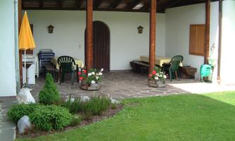 A cozy outdoor area with a covered terrace. Green spaces and colorful flowers create an inviting atmosphere.