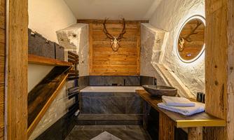 A stylish bathroom with wood and stone elements. The cozy atmosphere is complemented by a modern mirror and an elegant bathtub.