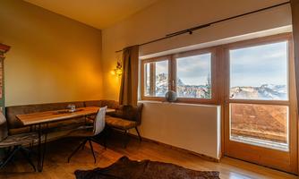 A cozy room with wooden details and a large window. From there, you have a beautiful view of the mountains.