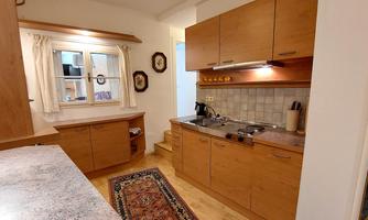 A modern kitchen with wooden furniture and a cozy atmosphere. The light gently falls through the window and highlights the practical arrangement of the appliances.
