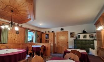 A cozy restaurant area with wooden furniture and round tables. The walls are adorned with wooden paneling and decorative elements.