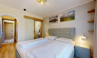 A modern bedroom with a double bed and appealing wall decoration. The room is bright and friendly, with wooden flooring and a cozy atmosphere.