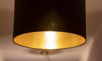 A dark ceiling lamp with a golden interior hangs from the ceiling. In the background, more similar lamps are visible.