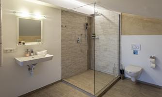 A modern bathroom with a glass shower and a large mirror. The walls are light, and the decor appears clean and elegant.
