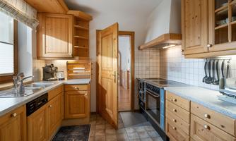 A cozy kitchen with wooden cabinets and modern cooking appliances. The light falls through the window, creating an inviting atmosphere.