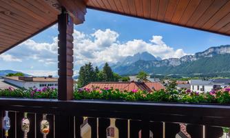 A beautiful view from a balcony of the mountains and the valley. In the foreground, colorful flowers are blooming.