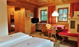 A cozy room with wooden paneling and two beds. In the room, there is a table, chairs, and a television.