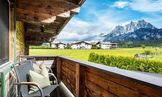 A beautiful balcony with a view of green meadows and impressive mountains. The scene conveys tranquility and a connection to nature.