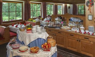 An inviting dining room with an extensive breakfast buffet selection. Wood-paneled walls and large windows create a bright, cozy atmosphere.
