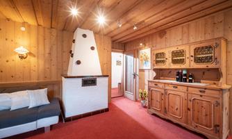 A cozy room with wood paneling and a fireplace. There is a sofa and a wooden cabinet with drinks.