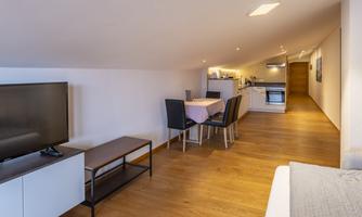 A modern loft with wooden floors. The open kitchen and dining area create an inviting atmosphere.