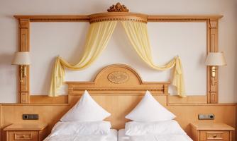 An elegant bedroom with two single beds and wood paneling. The decorative elements in yellow give the room a friendly atmosphere.