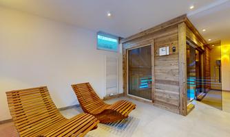 A relaxing wellness area with wooden lounge chairs and a modern sauna. The warm atmosphere invites you to unwind.
