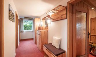 A bright hallway with wooden shelves and a cozy seating area. The window offers a view of the outdoor area.