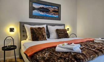 A cozy bedroom with a large bed and soft pillows. On the wall hangs a picture of a mountain landscape.