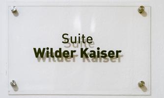 A transparent sign with the inscription "Suite Wilder Kaiser". The name is designed in an elegant font.