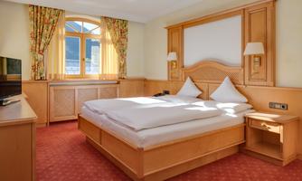 A cozy bedroom with a double bed and soft pillows. Large windows provide plenty of daylight and an inviting atmosphere.