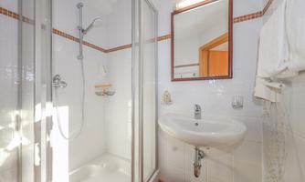 A modern bathroom with a shower and a sink. A bright and clean atmosphere with a large mirror.
