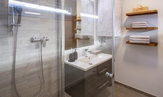 A modern bathroom with a shower and an elegant sink. Towels are neatly hung on a shelf.