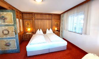 A cozy bedroom with two beds and wooden walls. The room has a warm, inviting ambiance and plenty of natural light.