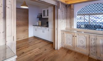 A modern designed kitchen with wooden shelves and a large window. The space has bright lighting and offers a cozy atmosphere.