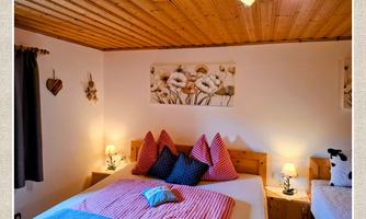 A cozy bedroom with a double bed and a single bed. The walls are painted light and adorned with decorative elements.