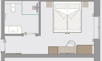 A simple floor plan representation of a room with a bathroom. The room contains a large bed, a table, and a chair.