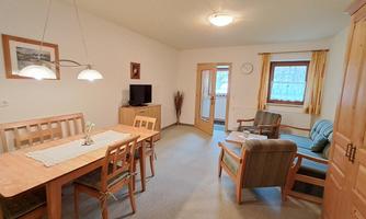 A cozy living room with a dining area and television. The room has a warm, inviting character.