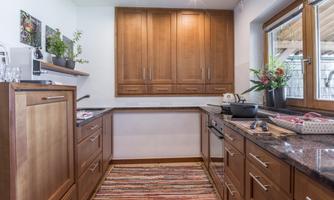 The kitchen is modern and bright, with wood-colored furniture and an elegant countertop. A rug with colorful stripes adds coziness to the space.