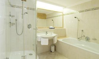 A modern bathroom with a shower and bathtub. Bright tiles and a large mirror create a friendly atmosphere.