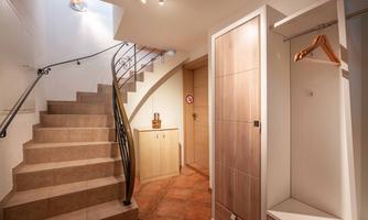 A modern hallway with a curved staircase and stylish walls. On the right side, there is a wardrobe with a coat hook.