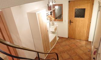 A bright entrance area with a wardrobe and a mirror. The door is made of wood and has a small window.