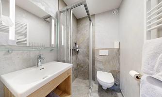 A modern bathroom with a shower and a sink made of light wood. The walls are painted in neutral colors, and there are large mirrors.