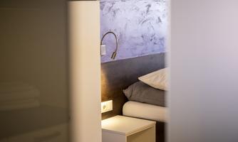 A modern bedroom with a bed, a nightstand lamp, and a stylish design. The walls are in soft colors.