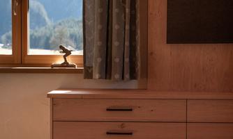 A bright room with a wooden cabinet and a window that offers a view of the mountains. The curtains are gray patterned.