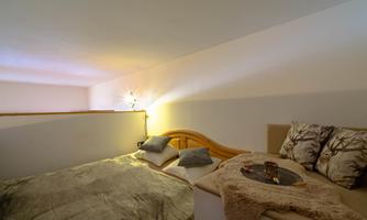 A cozy bedroom with a large bed and a tastefully furnished sitting area. Soft cushions and pleasant lighting create a relaxed atmosphere.