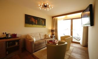 A cozy living space with a comfortable sofa and two armchairs. Large windows provide plenty of daylight and offer a view outside.