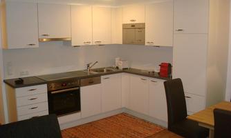 A modern kitchen with white cabinets and black countertops. In the corner, there is a table and chairs that look cozy.