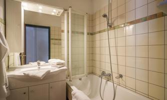 A modern bathroom with a bathtub and shower cabin. Fresh towels are placed on the sink.