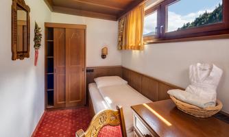 A simple room with a single bed and a table. A wardrobe and a window overlooking nature are also available.