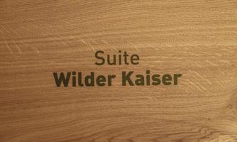 A wooden sign with the inscription "Suite Wilder Kaiser". The design is simple and elegant.