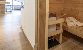 A modern sauna with wooden paneling and a relaxation area. Towels are ready to enjoy relaxing moments.