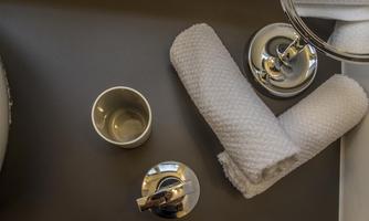 A bathroom with a mirror, a cup, and a towel. The surface is dark and clean.