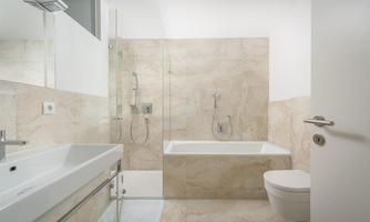 A modern bathroom with a shower and a bathtub. The walls are in bright, neutral tones.