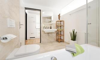 A modern bathroom with a bathtub, a sink, and a plant. The walls are bright and the decor is simple and elegant.